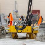 A yellow robotic rover kicks up sand in a mobility test bin.
