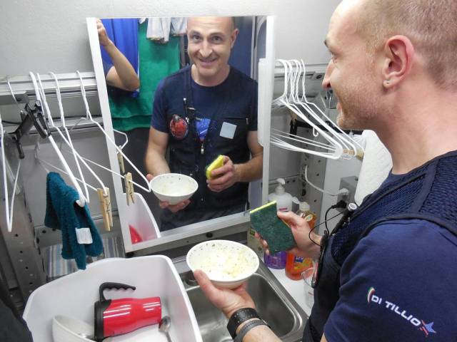 HERA crew member Pietro Di Tillio uses a sponge to wash his dish by hand inside the habitat. 