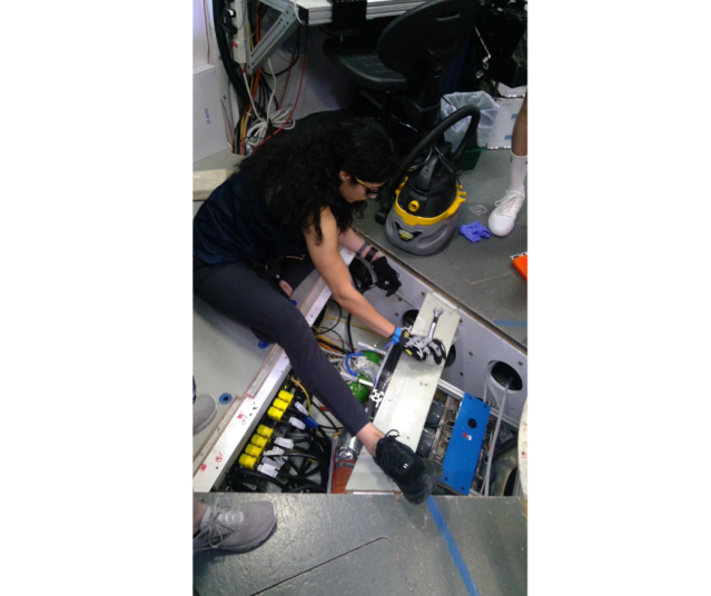 HERA crew member Monique Garcia inspects tanks and wires beneath a floor panel of a habitat that NASA uses to simulated space missions.
