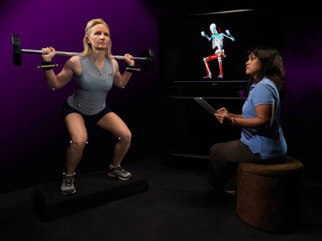 A biomechanical engineer monitors a subject as she performs a squat exercise