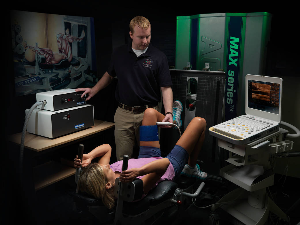 Dr. Meghan Everett performs resistance exercise with an inflation cuff around the lower limb as Dr. Kyle Hackney examines