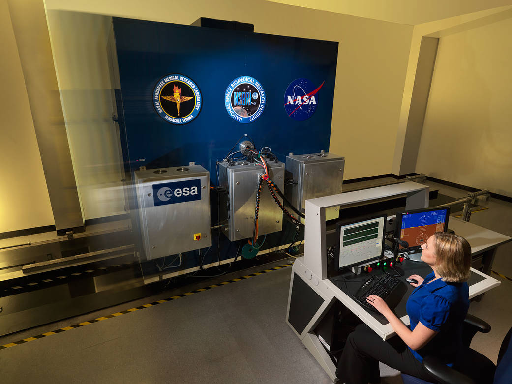 A researcher runs a motion simulation profile in the Tilt Translation Sled device in the Neurosciences Laboratory.
