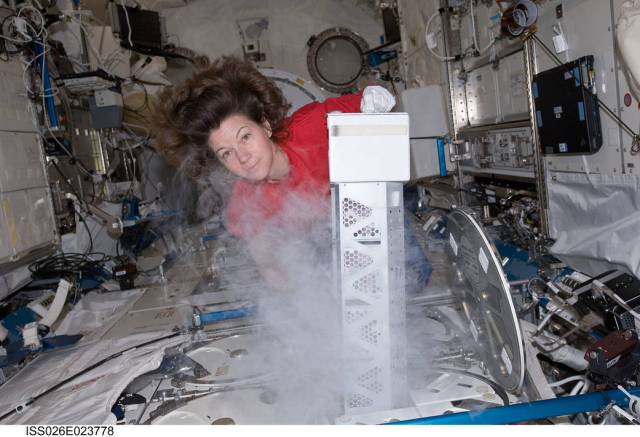 NASA astronaut Catherine (Cady) Coleman preparing to insert samples into a freezer