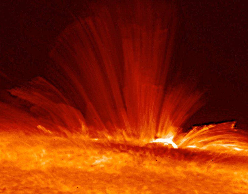 Vivid orange streamers of super-hot, electrically charged gas (plasma) arc from the surface of the Sun, revealing the structure 