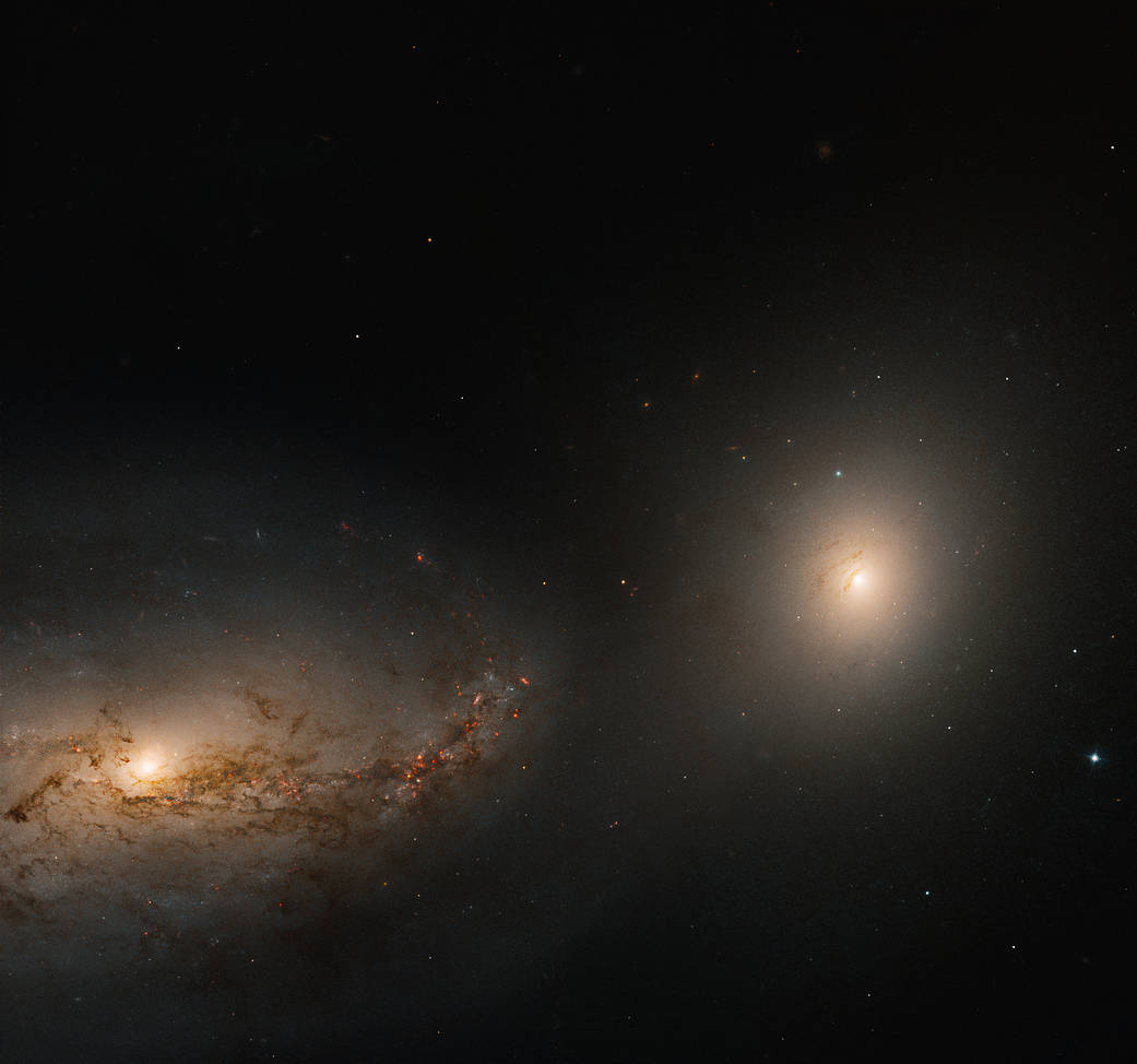 Lower left: large spiral galaxy with reddish brown dust lanes extends toward the center of the image. Center right: bright elliptical galaxy
