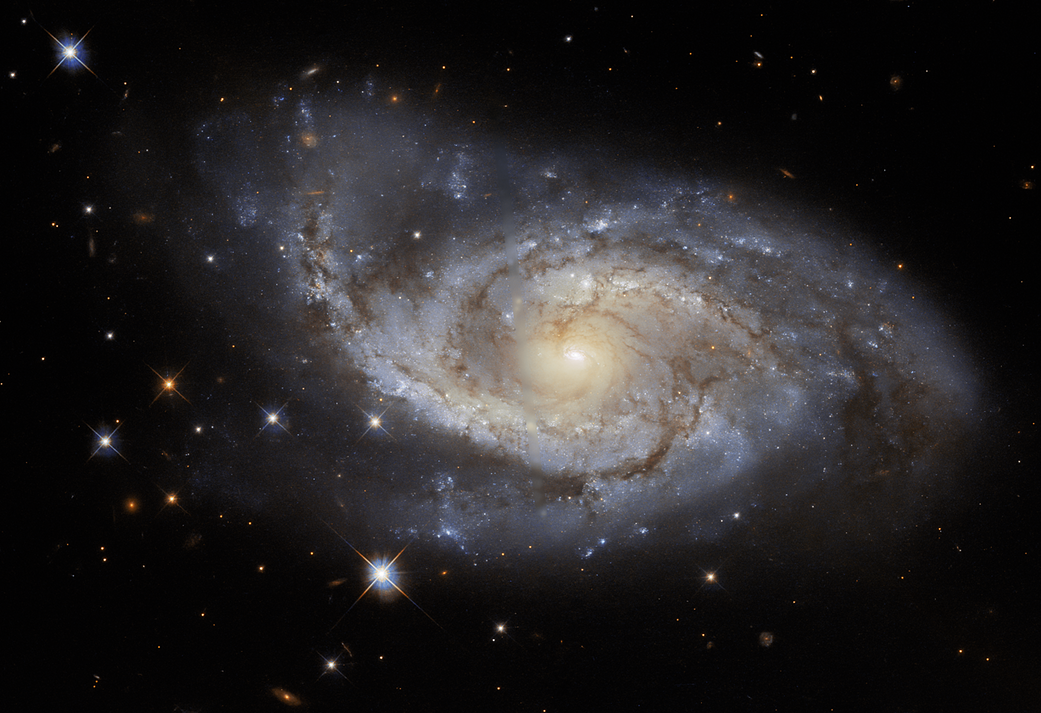 face on spiral galaxy at center. A spiral of bright star-forming regions and dark dust lanes