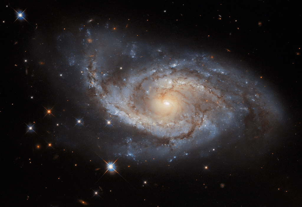 face on spiral galaxy at center. A spiral of bright star-forming regions and dark dust lanes