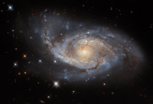 face on spiral galaxy at center. A spiral of bright star-forming regions and dark dust lanes