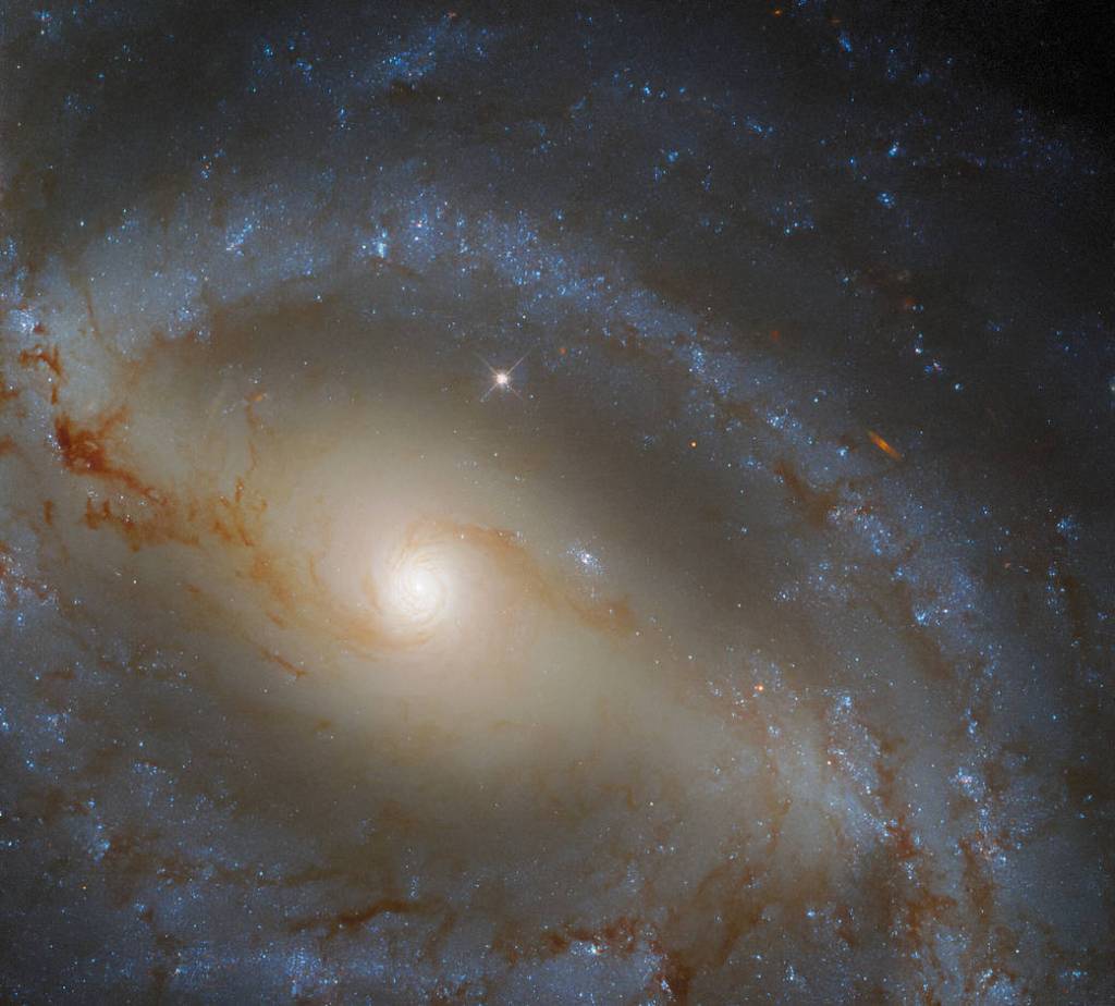 Large spiral galaxy with a bar of stars bisecting the image from the upper left to the lower right.
