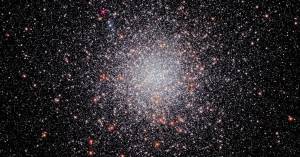 Center of the image is filled with a sphere of white stars. A smattering of orang-white stars dots the sphere. They are set against a black background that holds a smattering of stars.