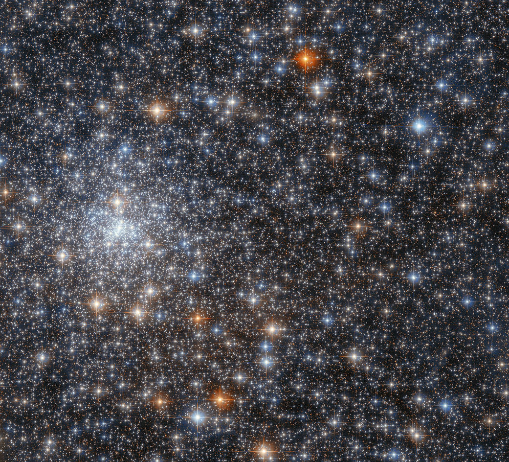bright cluster of blue-white stars at left center. frame filled with red, reddish-gold, blue, and blue-white stars