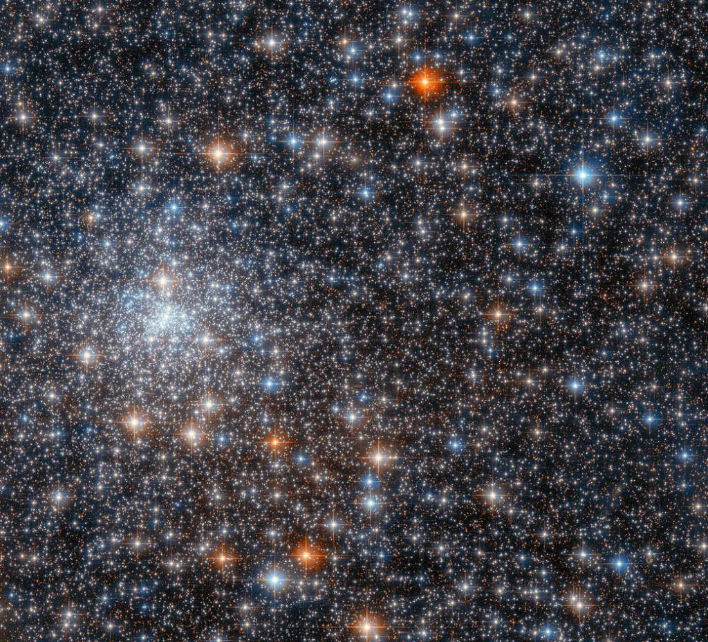 bright cluster of blue-white stars at left center. frame filled with red, reddish-gold, blue, and blue-white stars
