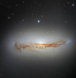 Bright galaxy seen from the side. It has a large central bulge of stars and dust cutting across it lengthwise,