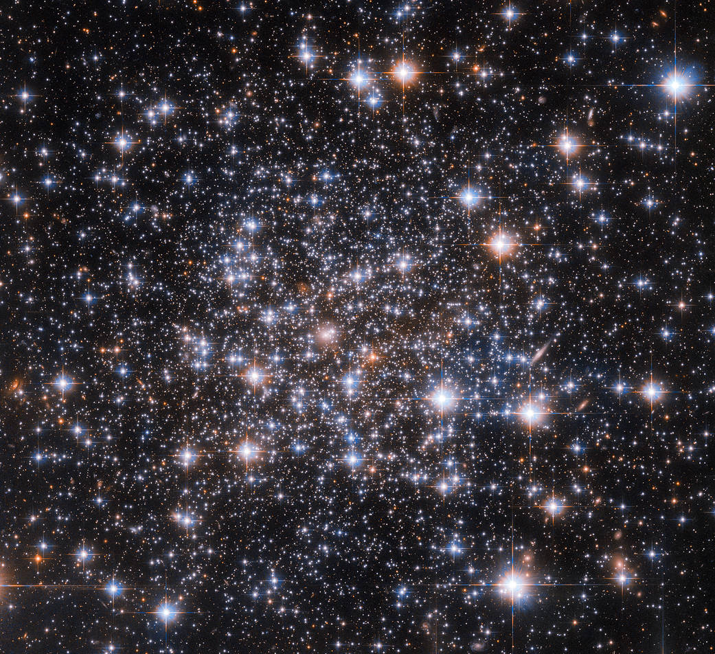 bright, rounded cluster of white stars, some with blue or red halos.