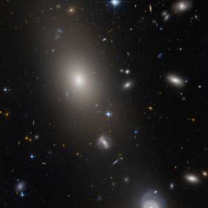 A field of galaxies. A large elliptical galaxy in the top left quadrant, with more distant galaxies visible through its fringes.