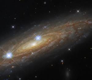 Spiral galaxy stretches from lower left to upper right of the image. Two bright foreground stars are also in the image.