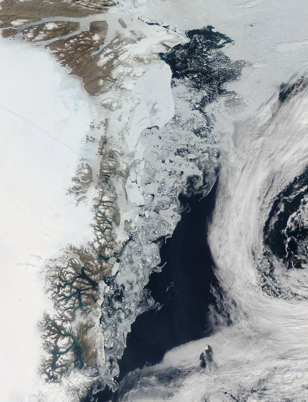 Swirls of sea ice along the coast and dark blue waters of the Arctic