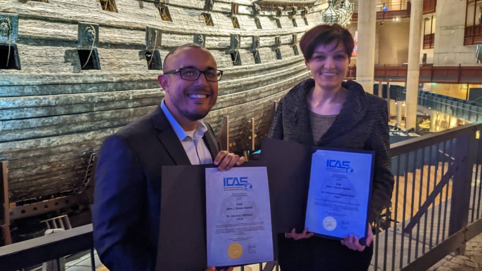 Man and woman holding up award certificates for photo.