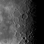 A close-up image of the Moon's surface, which fades from smooth gray at the left, to craggy craters and black shadow at the right.
