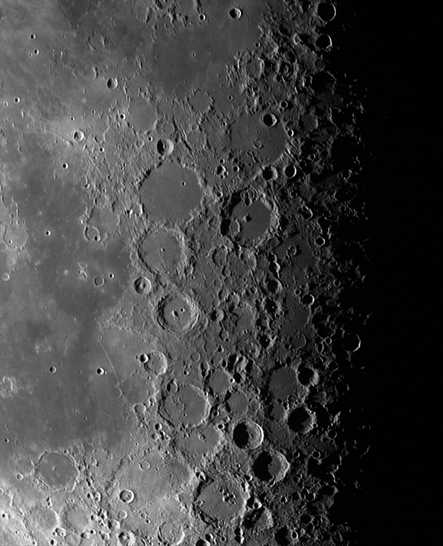 A close-up image of the Moon's surface, which fades from smooth gray at the left, to craggy craters and black shadow at the right.