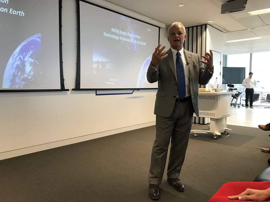 Man speaking in front of two screens