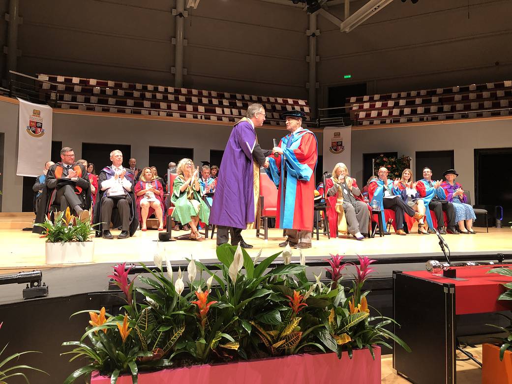 Two men shake hands on a stage
