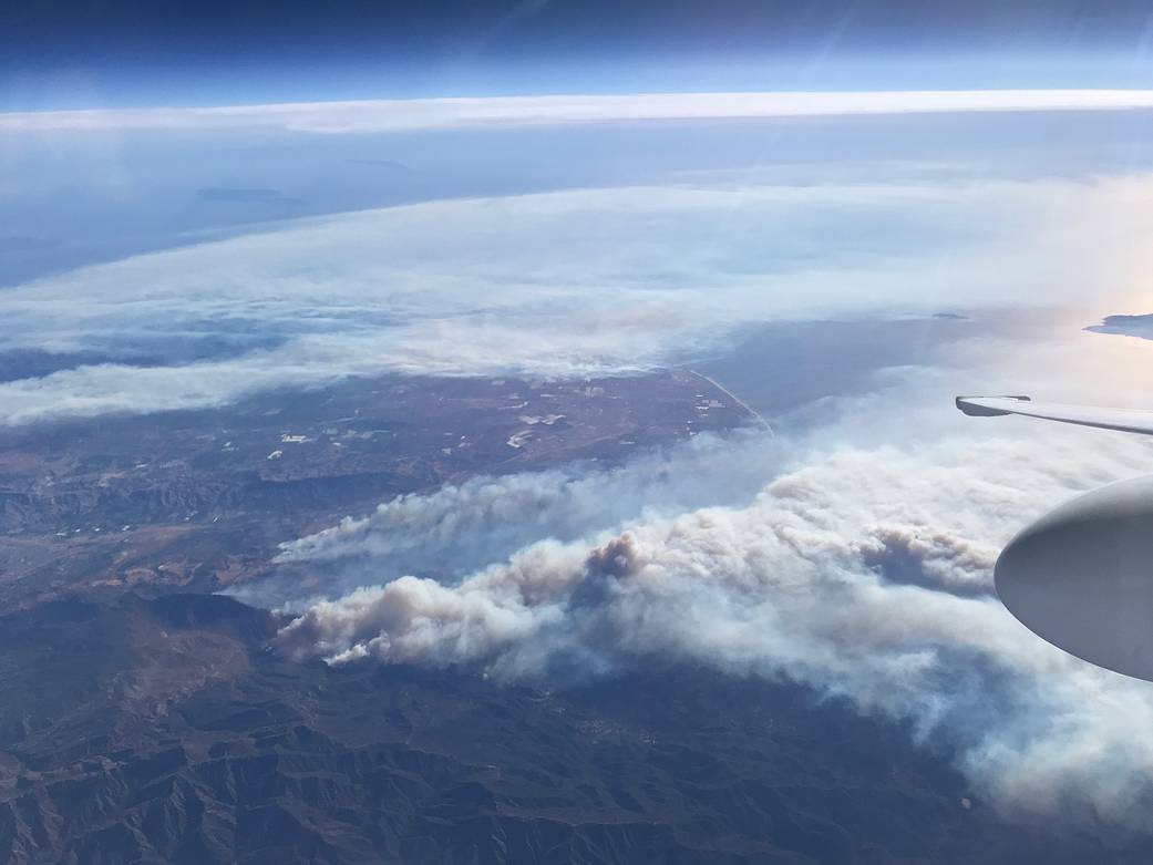View from aircraft of smoke plume rising from land below