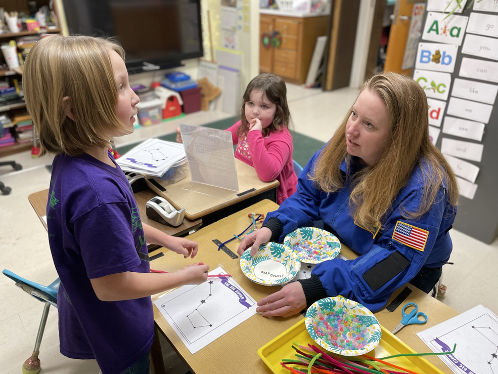 Students working on an activity while at their desk with an adult