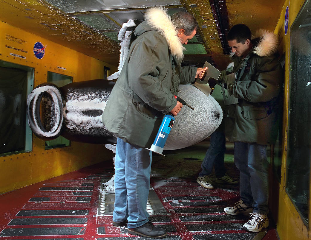 Technicians taking measurement of ice accretions inside the icing research wind tunnel.