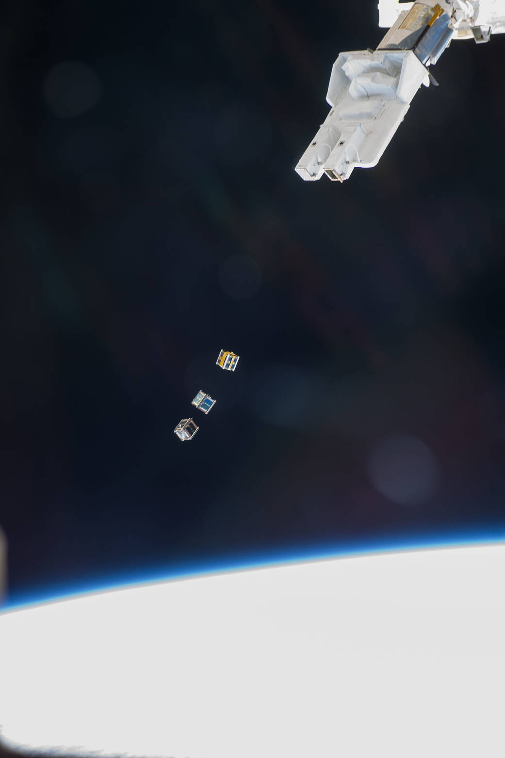 Three nanosatellites, known as Cubesats, are deployed from a Small Satellite Orbital Deployer (SSOD) attached to the Kibo labora