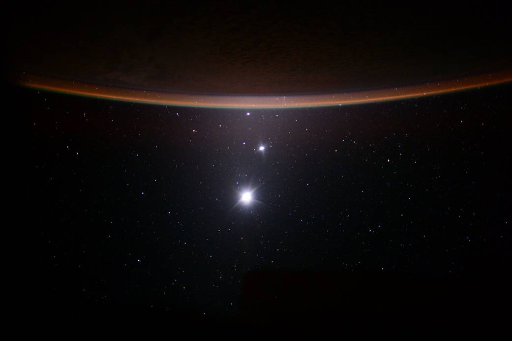A view of the Moon, Venus and Jupiter with the Earth's atmospheric golden glow in the foreground at night was taken from the space station.