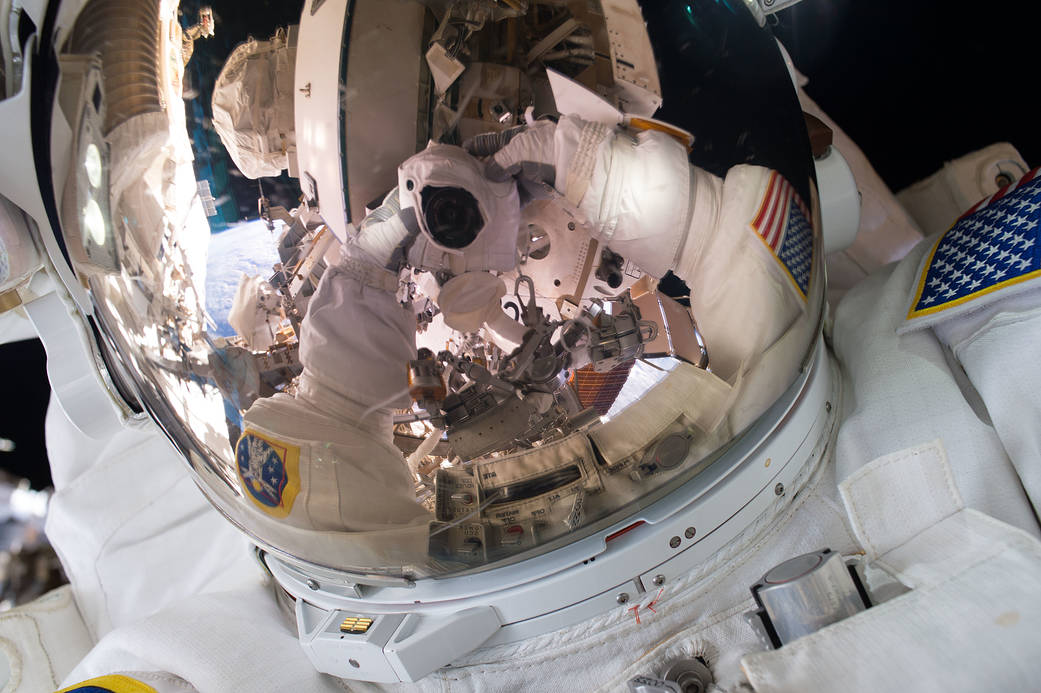 Astronaut photograph reflected in space helmet visor during spacewalk