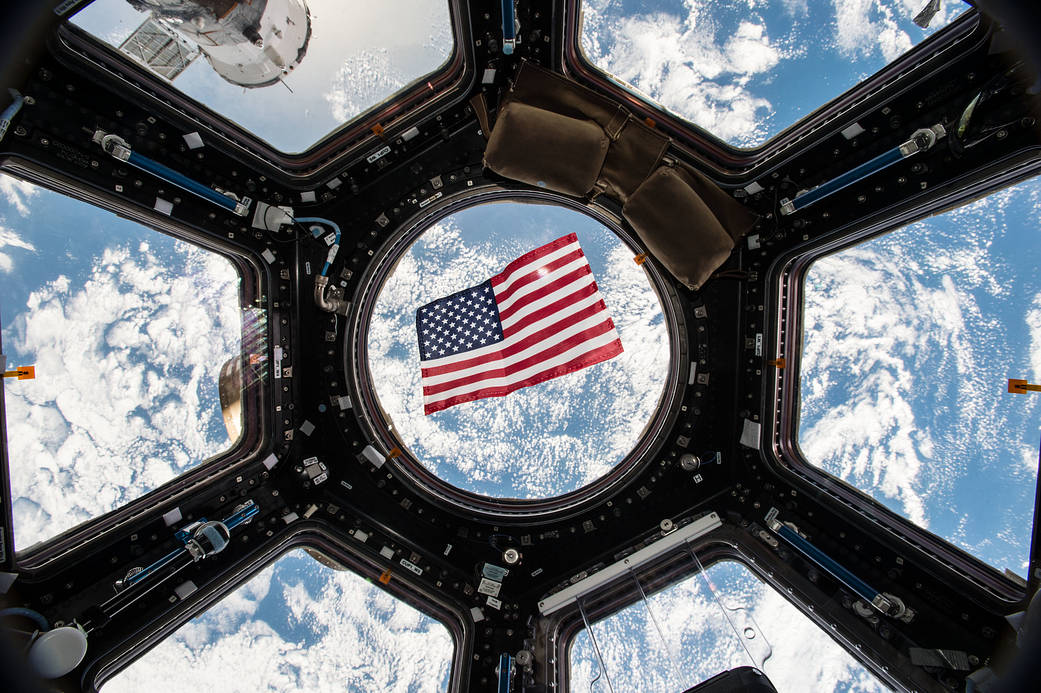 American flag in the window of the cupola aboard the International Space Station
