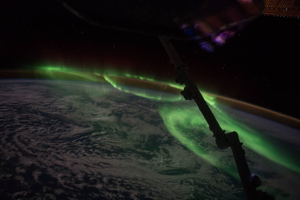 Looping green aurora over Earth with clouds and sea visible below