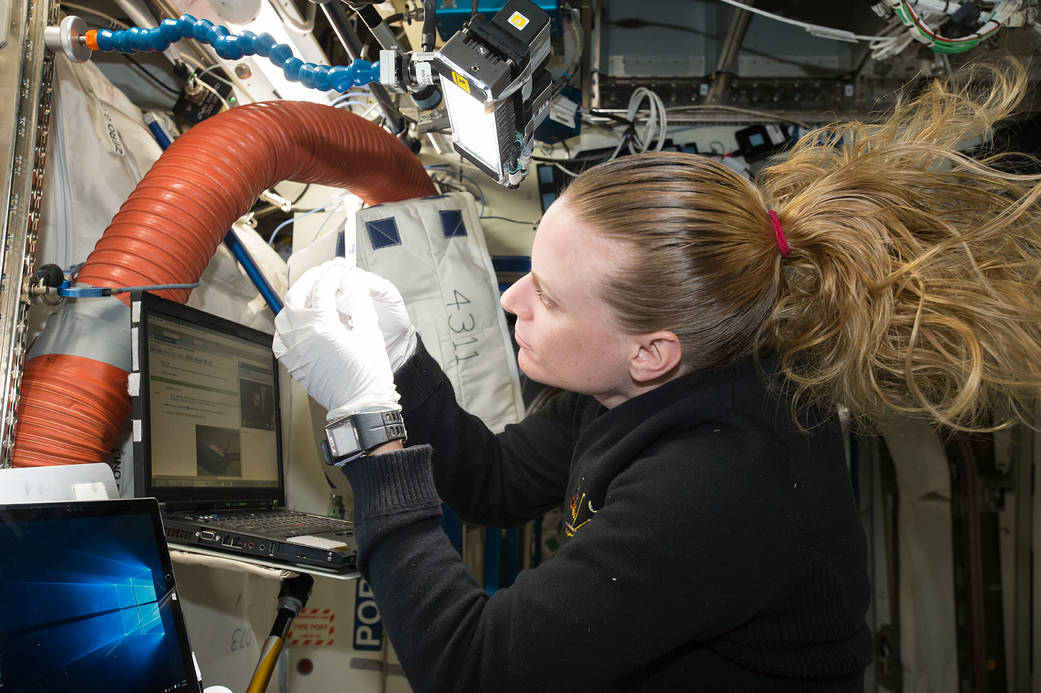 NASA astronaut Kate Rubins looking at DNA sample inside space station laboratory