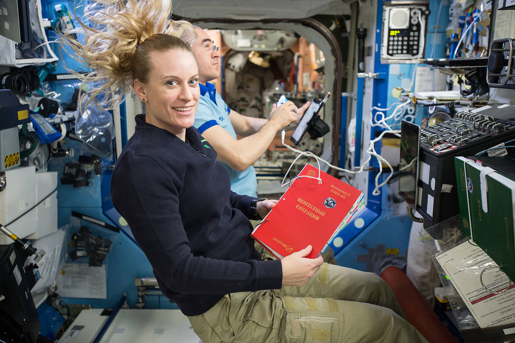 Astronaut Kate Rubins Holds a Reference Guide
