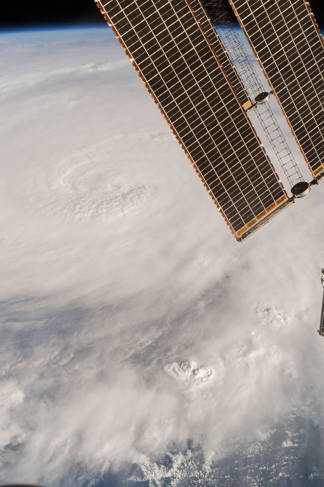 Hurricane Matthew photographed from space station window with solar arrays visible in the upper right corner