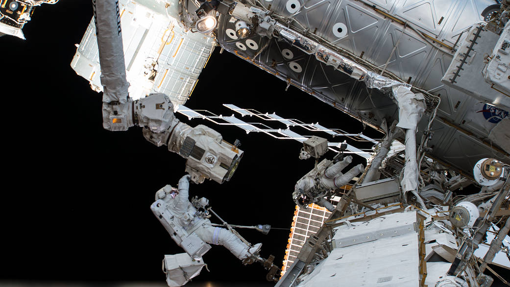 Two astronauts in spacesuits at work outside space station