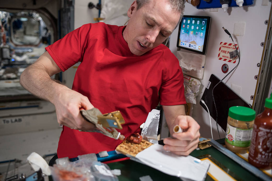 Commander Drew Feustel prepares a meal inside the Unity module