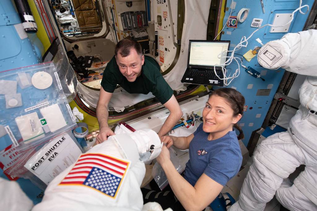 NASA astronauts Nick Hague and Christina Koch work on U.S. spacesuits