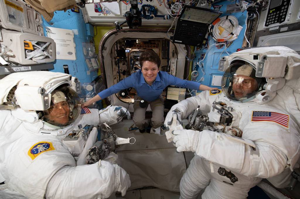 Astronaut Anne McClain assists fellow astronauts Christina Koch and Nick Hague