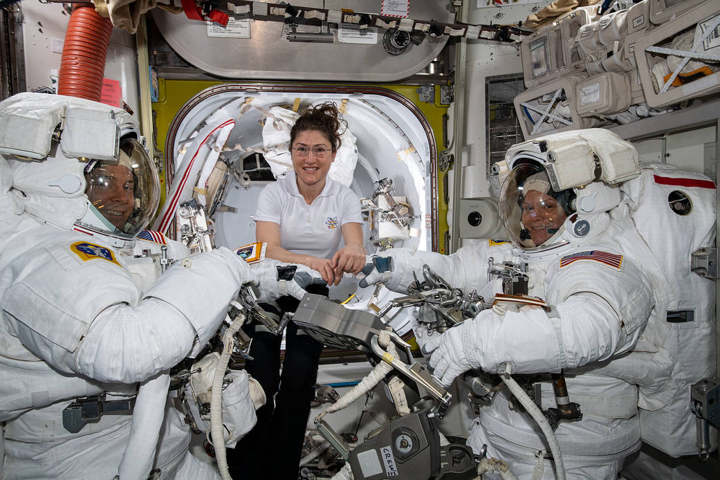 Astronaut Christina Koch assists spacewalkers Nick Hague and Anne McClain
