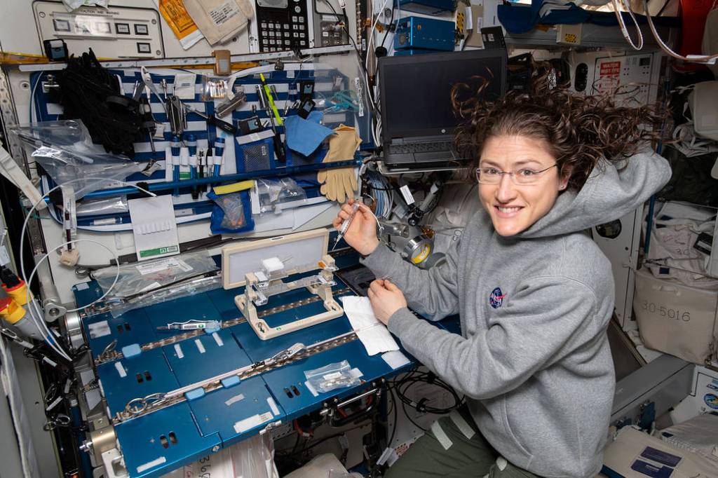 NASA astronaut Christina Koch checks out hardware for the Capillary Structures experiment