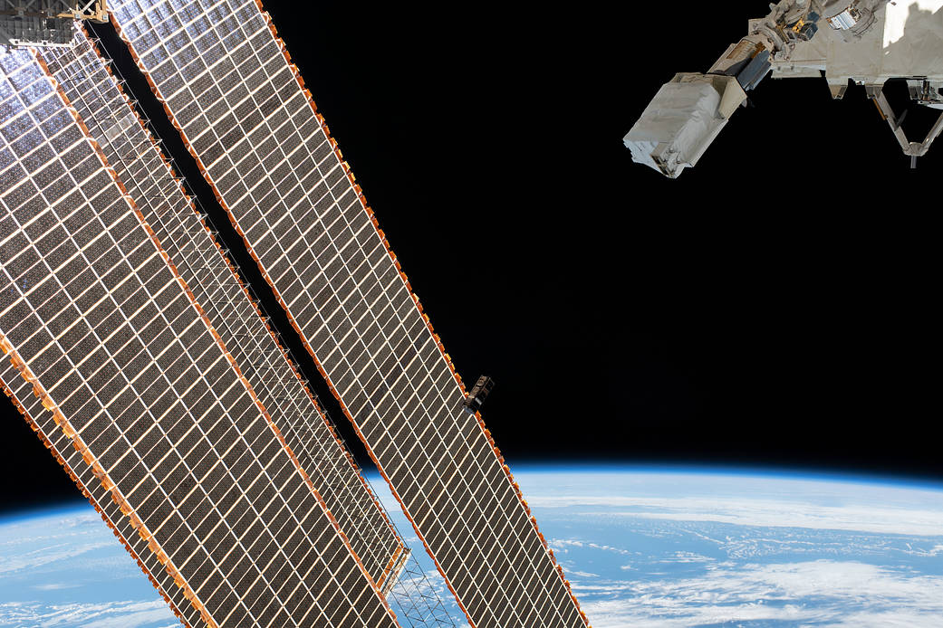 A CubeSat goes past the International Space Station's solar arrays
