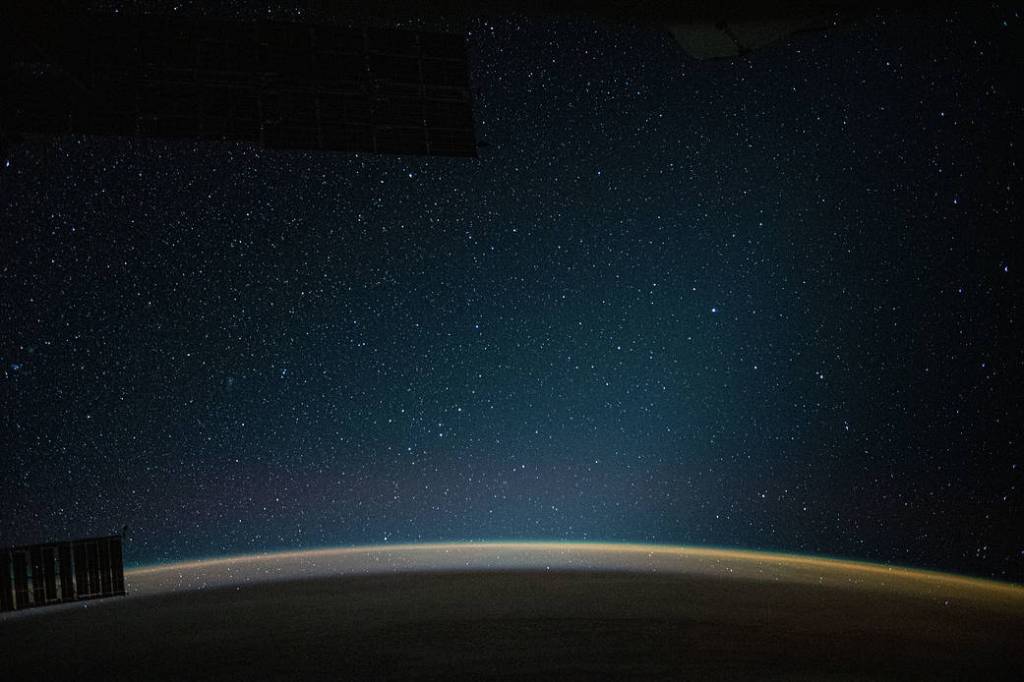 An atmospheric glow blankets Earth beneath a starry night sky