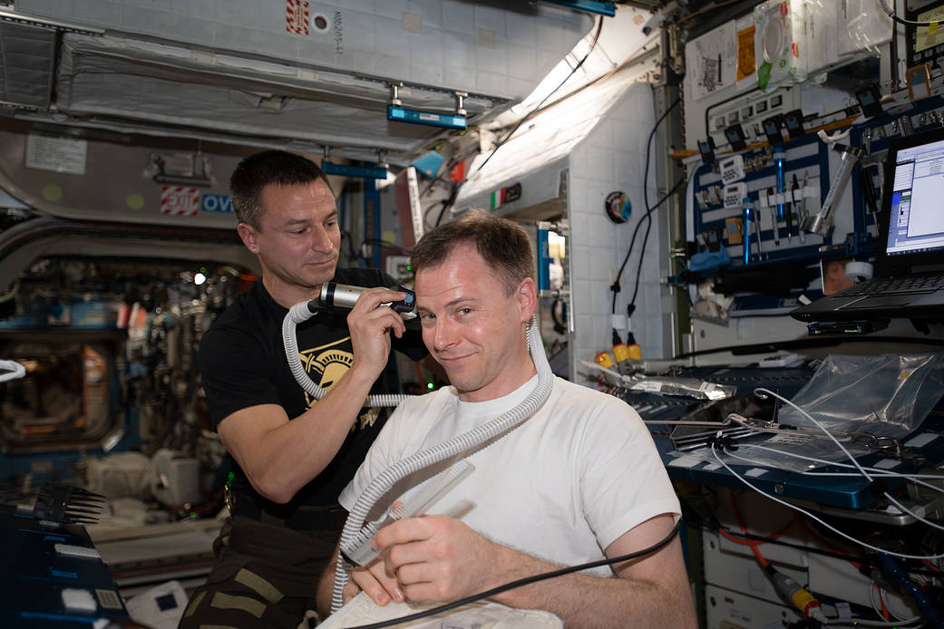Flight Engineer Andrew Morgan trims the hair of fellow astronaut Nick Hague