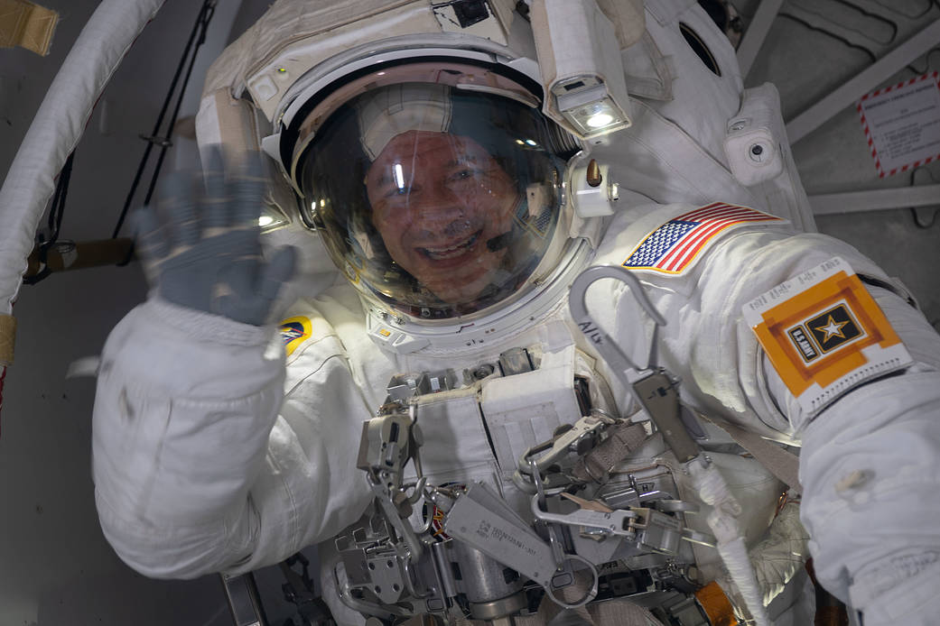 NASA astronaut Andrew Morgan waves from inside the Quest airlock