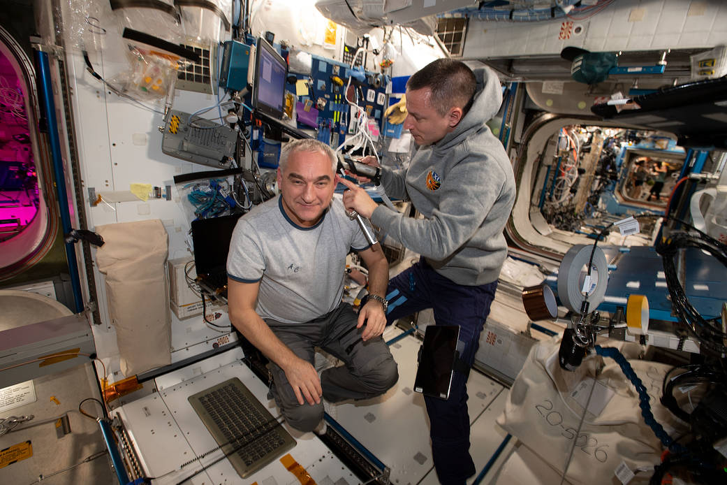 Astronaut Andrew Morgan trims the hair of cosmonaut Alexander Skvortsov