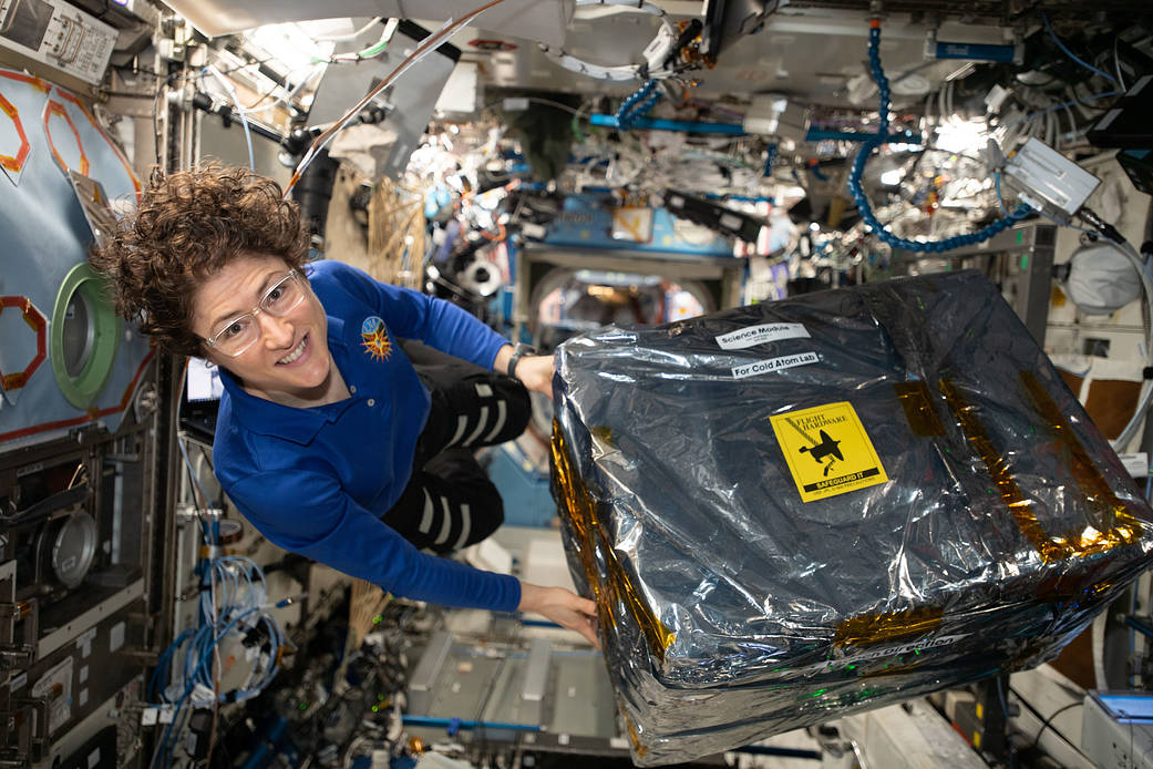 NASA astronaut Christina Koch handles science hardware