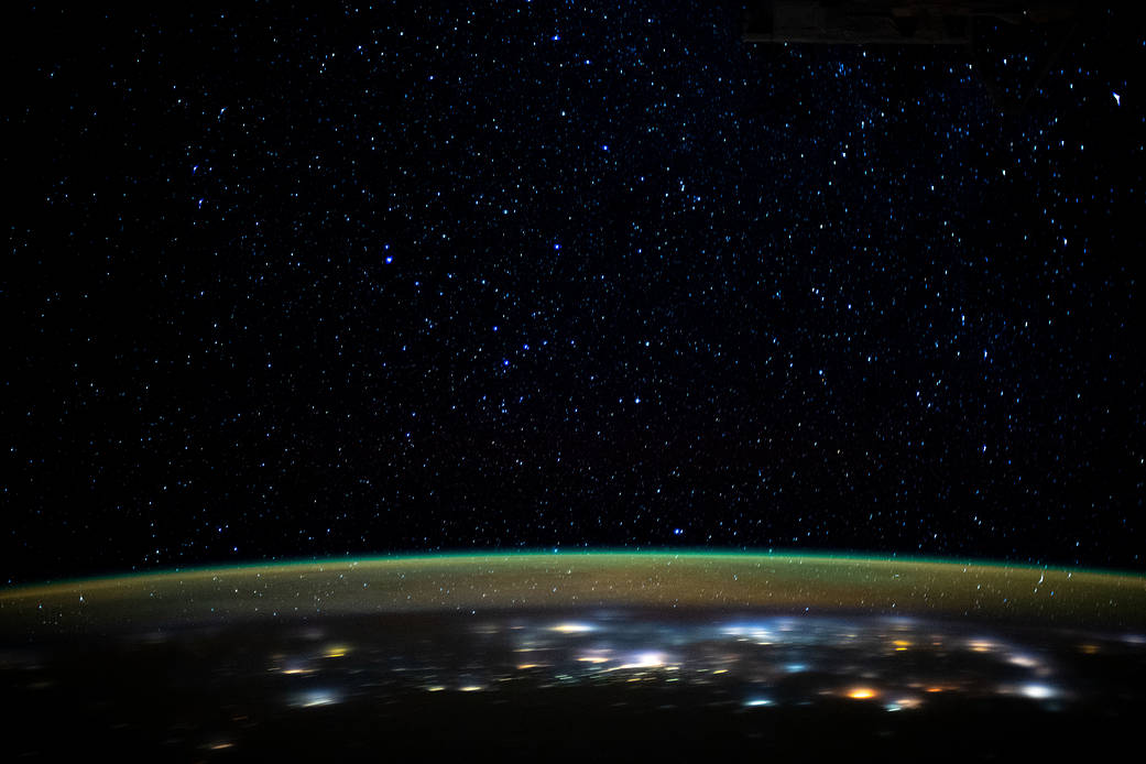 Stars glitter in the night sky above Earth's atmospheric glow